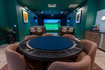 A round table with a blue tabletop is surrounded by brown chairs in a room with green walls.